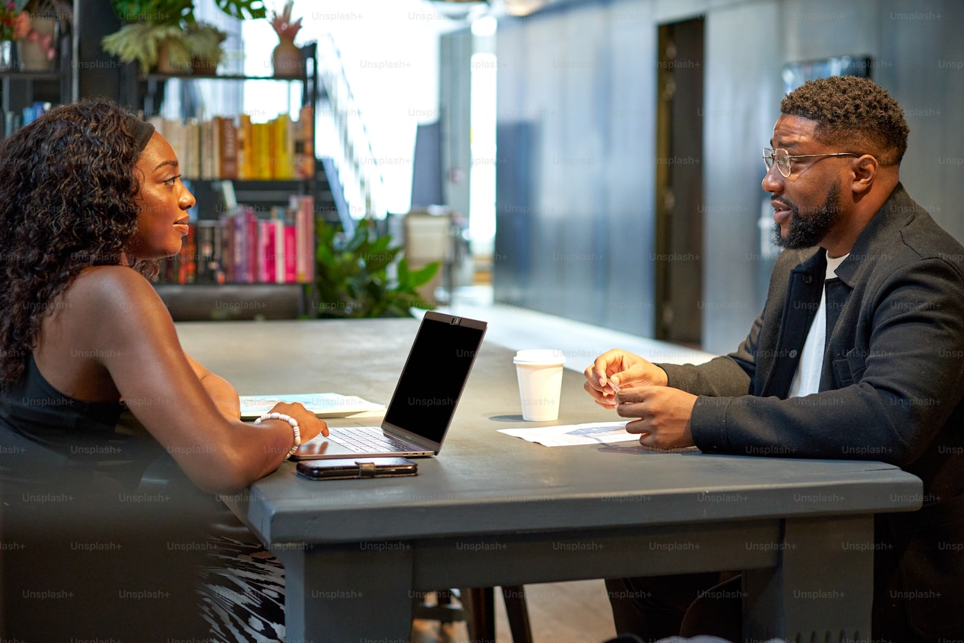 Two confident Black business professionals discussing audit documents in a modern office